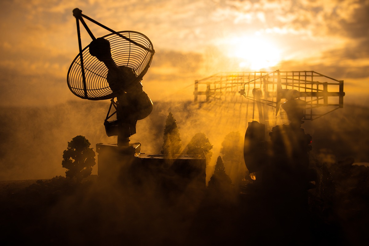 Silhouettes of satellite dishes or radio antennas against night sky. Space observatory or Air defence radar over dramatic sunset sky. Creative artwork decoration. Selective focus
