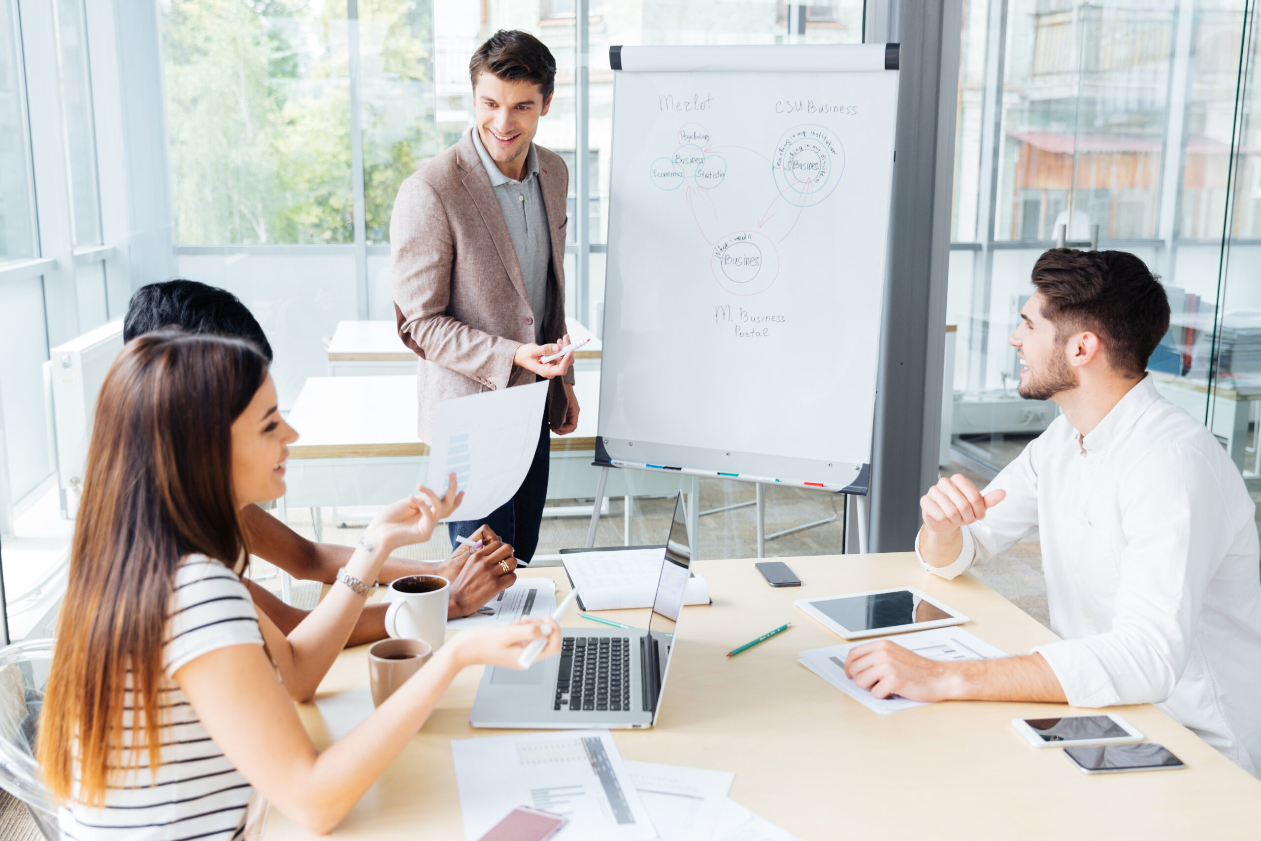Happy attractive young businessman making presentation for business people in office