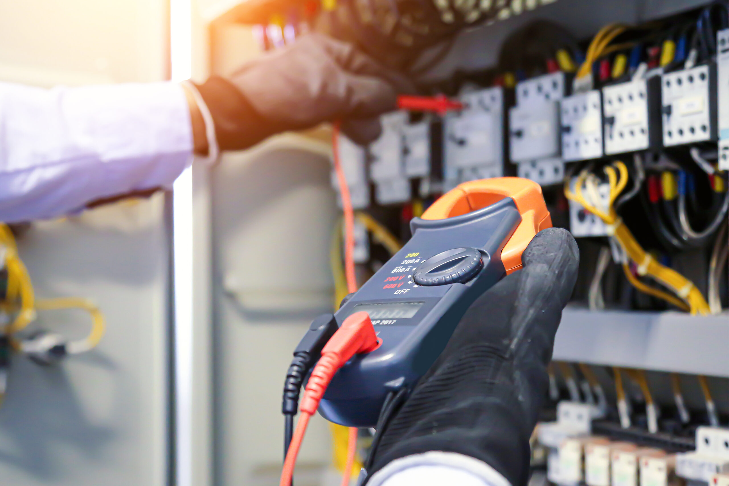 Electricity and electrical maintenance service, Engineer using measuring equipment checking electric current voltage at circuit breaker terminal block and cable wiring main power distribution board.